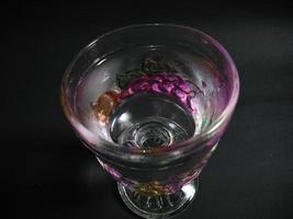 a transparent fruit patterned glass filled with mineral water on a black background. photo