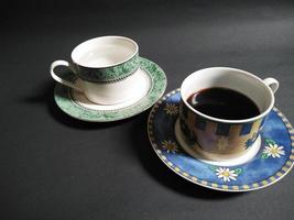 taza de té y taza de café sobre un fondo negro. foto