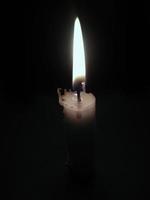 a small candle burning in a pitch dark atmosphere photo