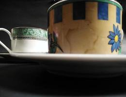 teacup, coffee cup and transparent fruit patterned glass filled with mineral water on a black background. photo