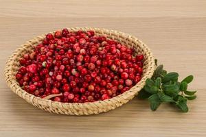 arándano rojo en una cesta sobre fondo de madera foto