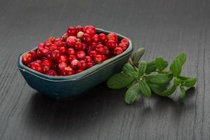 arándano rojo en un recipiente sobre fondo de madera foto