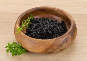 Black caviar in a bowl on wooden background photo