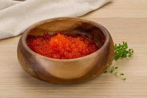 Red caviar in a bowl on wooden background photo