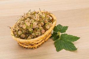 White currant in a basket on wooden background photo