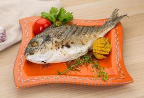 dorado a la parrilla en el plato y fondo de madera foto