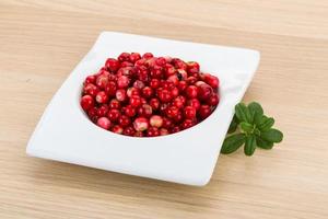 Cowberry in a bowl on wooden background photo