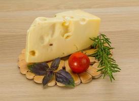 Maasdam cheese on wooden board and wooden background photo