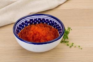 Red caviar in a bowl on wooden background photo