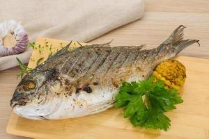 Grilled dorado on wooden board and wooden background photo