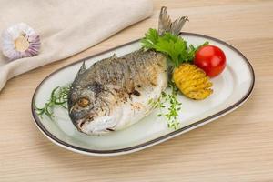 Grilled dorado on the plate and wooden background photo