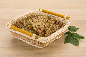 White currant in a basket on wooden background photo