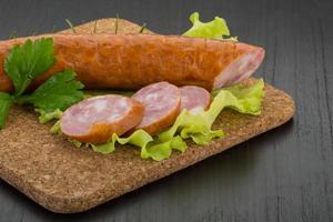 Sausage on wooden board and wooden background photo