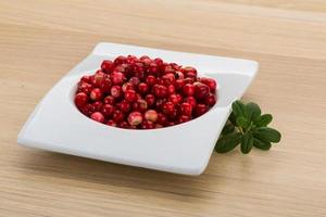 Cowberry in a bowl on wooden background photo