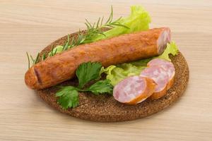 Sausage on wooden board and wooden background photo