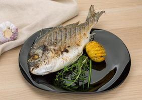 Grilled dorado on the plate and wooden background photo