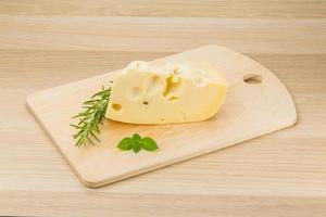 Maasdam cheese on wooden board and wooden background photo