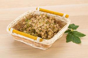 White currant in a basket on wooden background photo