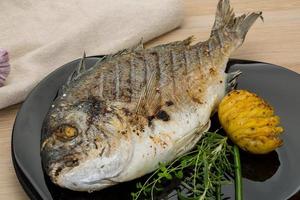 Grilled dorado on the plate and wooden background photo