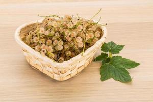 White currant in a basket on wooden background photo