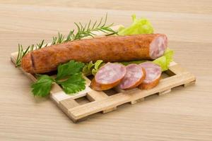 Sausage on wooden board and wooden background photo