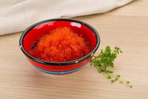 Red caviar in a bowl on wooden background photo