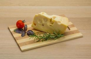 Maasdam cheese on wooden board and wooden background photo