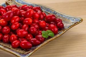 Cornus on the plate and wooden background photo