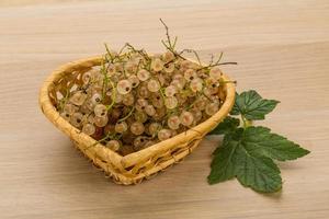 White currant in a basket on wooden background photo