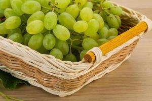 Green grapes on the plate and wooden background photo