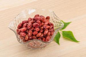 frijoles rojos en un recipiente sobre fondo de madera foto