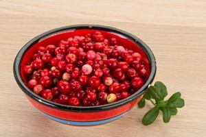 arándano rojo en un recipiente sobre fondo de madera foto