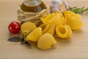 Raw pasta on wooden background photo