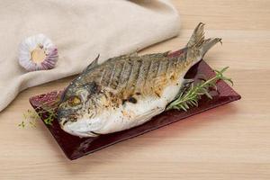 Grilled dorado on the plate and wooden background photo