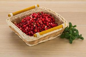 Cowberry in a basket on wooden background photo