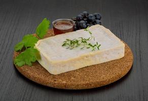 queso brie sobre tablero de madera y fondo de madera foto