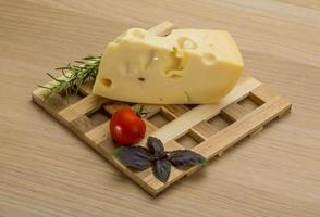 Maasdam cheese on wooden board and wooden background photo