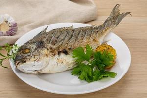 Grilled dorado on the plate and wooden background photo