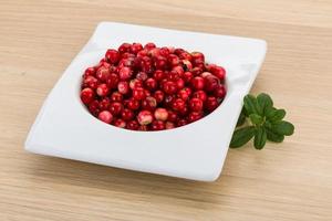 Cowberry in a bowl on wooden background photo