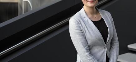 mujer profesional anónima con camisa negra y chaqueta de traje gris en un entorno urbano foto