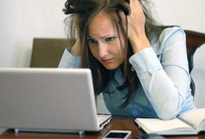 mujer con laptop y teléfono inteligente que parece preocupada foto