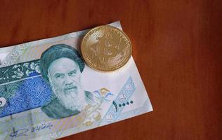 20 June 2022 - Tehran, Iran - A shiny Bitcoin on a 1000 Rial banknote photo