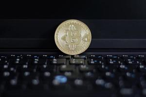 Shiny Bitcoin on laptop keyboard photo