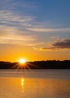 rayos de sol al amanecer sobre el lago con nutria foto