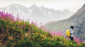 Excursionista femenina con nordic walk pols caminata cuesta abajo en las verdes montañas del Cáucaso sendero para caminatas en la naturaleza de primavera día lluvioso. actividades recreativas y estilo de vida saludable foto