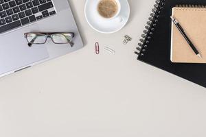 Flat lay office desk table with laptop, notebook, eyeglasses and cup of coffee. Workspace with copy space photo