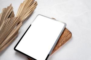 Digital tablet computer with isolated screen on office desk. At home interior with palm leaves photo