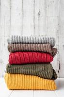 pila de suéteres cálidos de otoño sobre fondo blanco de madera foto