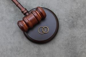 tema de la ley. Anillos de boda de mazo de juez sobre fondo gris de piedra de hormigón. procedimientos de divorcio. mazo de juez que decide sobre el matrimonio, el divorcio, el acuerdo matrimonial, la legalidad del divorcio. foto