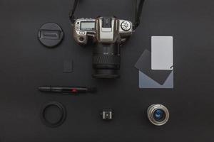 Photographer workplace with dslr camera system, camera cleaning kit, lens and camera accessory on dark black table background. Hobby travel photography concept Flat lay top view copy space photo